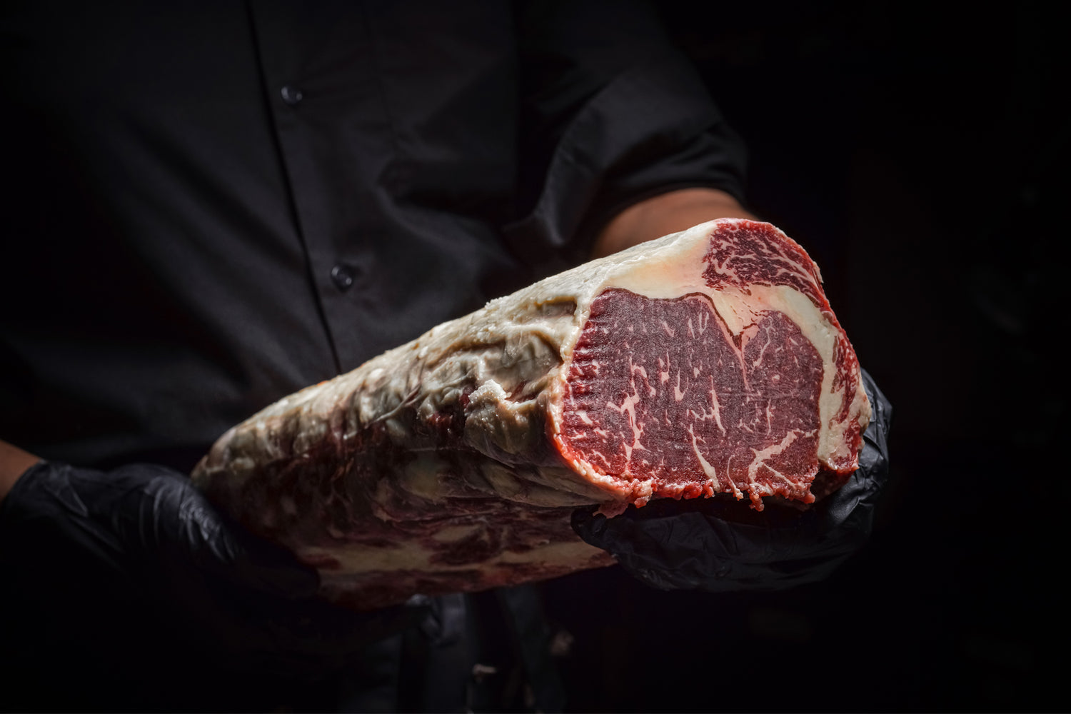 A chef holding a piece of dry-aged beef exudes elegance, bringing the Michelin-starred dining experience right into your home