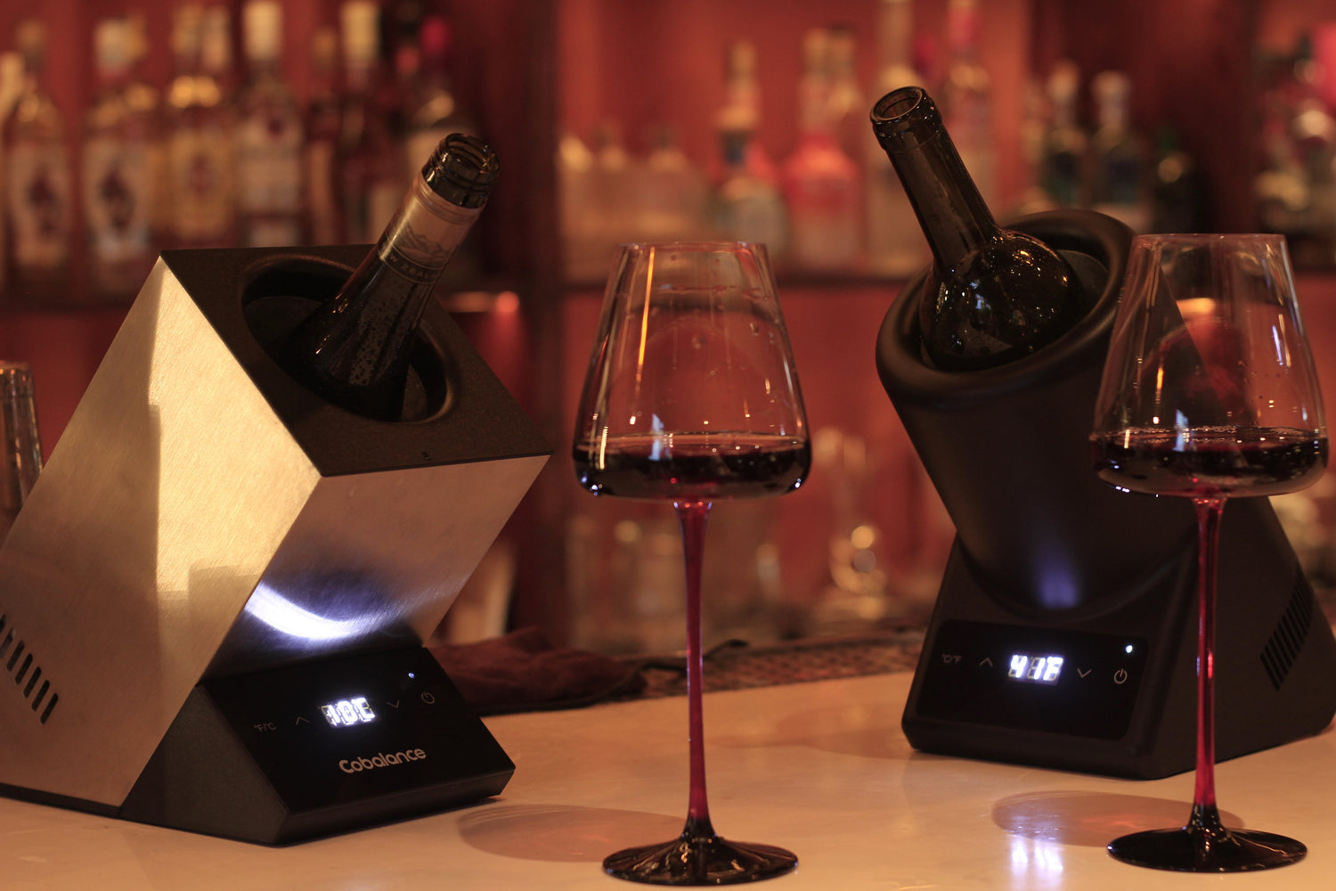 A contemporary home bar setup featuring two sleek, stainless steel wine coolers. Each cooler is equipped with a digital display, LED lighting, and can accommodate single a wine bottle, ensuring optimal temperature.